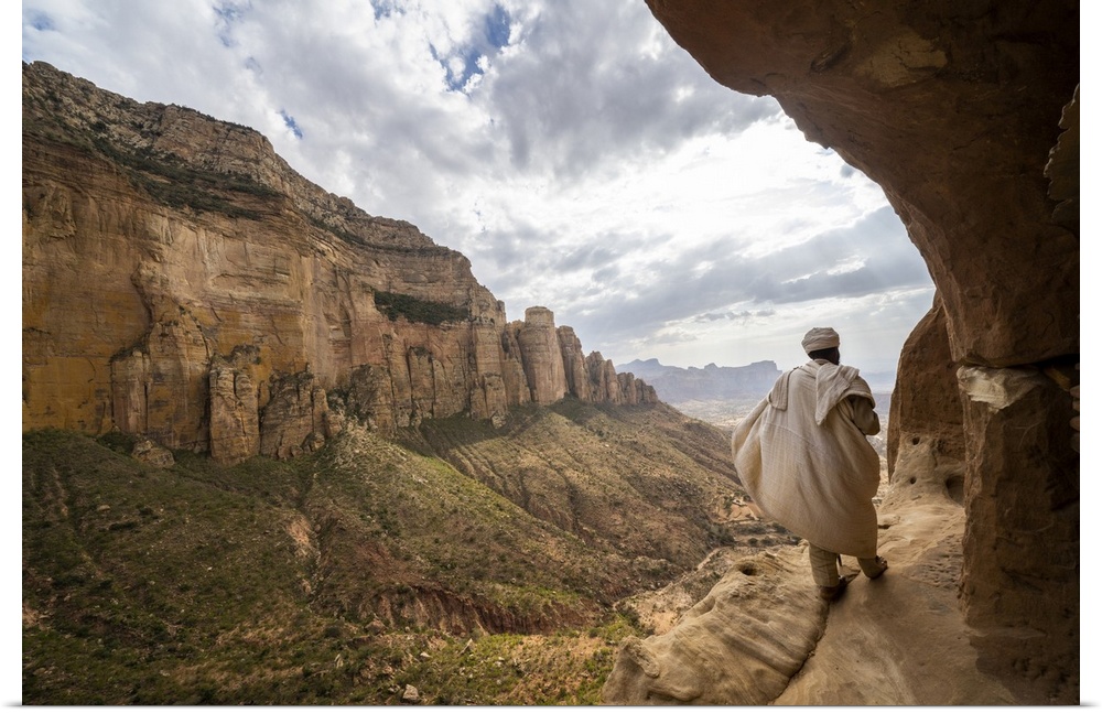 Rear view of priest walking on access trail to the rock-hewn Abuna Yemata Guh church, Gheralta Mountains, Tigray region, E...