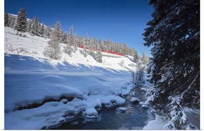 Rhaetian Railway on the Chapella Viadukt surrounded by snowy woods, Switzerland