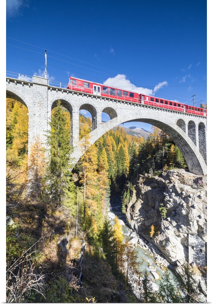 The red train on viaduct surrounded by colorful woods, Cinuos-Chel, Canton of Graubunden, Engadine, Switzerland