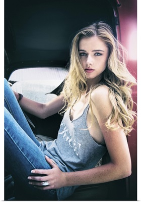 Blond girl wearing jeans sitting in an old pick up truck