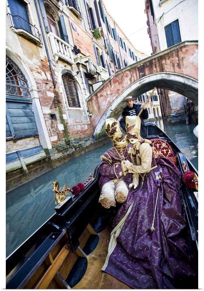 Couple in Masquerade outfits kissing in Gondola underneath bridge, Venice, Italy