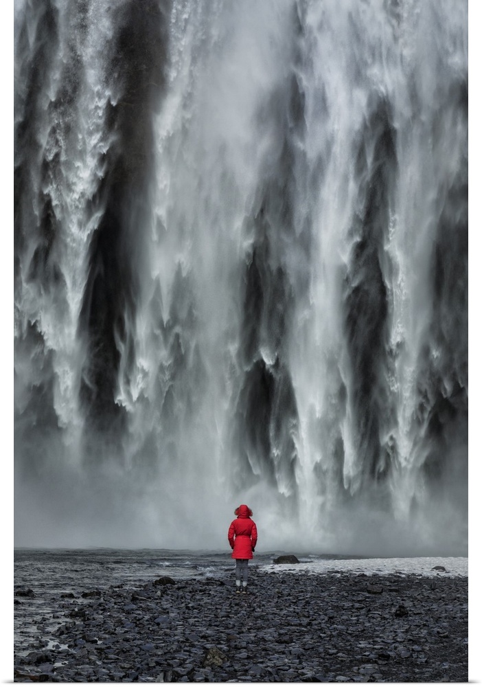 Woman staring into Skogafoss waterfall in Iceland.