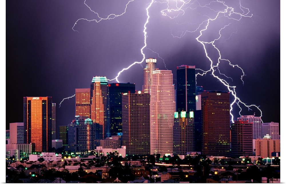 Photograph of lit up skyline at night with storm clouds overhead.