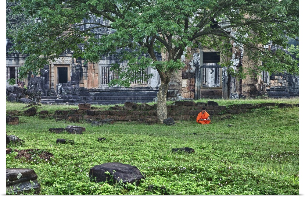 Monk reading in grass in front of religious temples in Angkor Wat, Cambodia