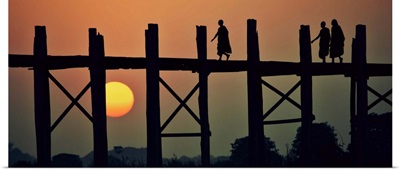 Monks walking across the Ubein Bridge in Burma at sunset