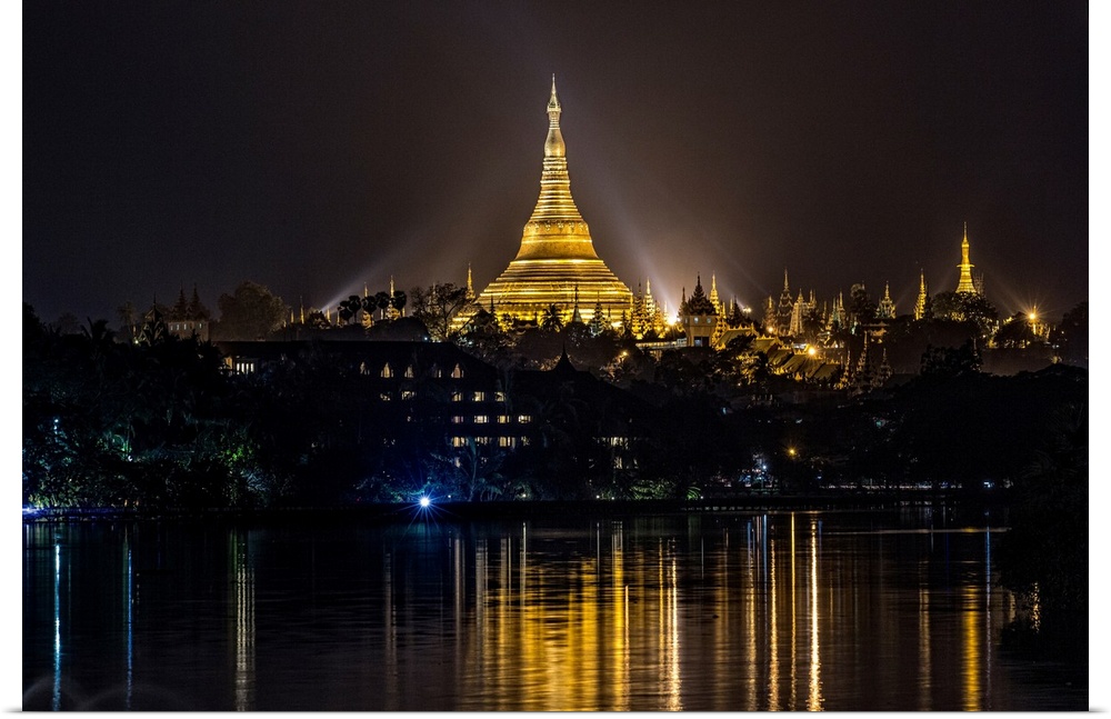 The Shwedagon Pagoda reflecting in the water after dark in Yangon.