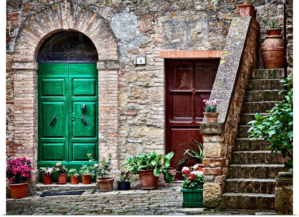 A rustic city street and ancient home built from stone and brick with brightly painted doorways lined with plants in terra...