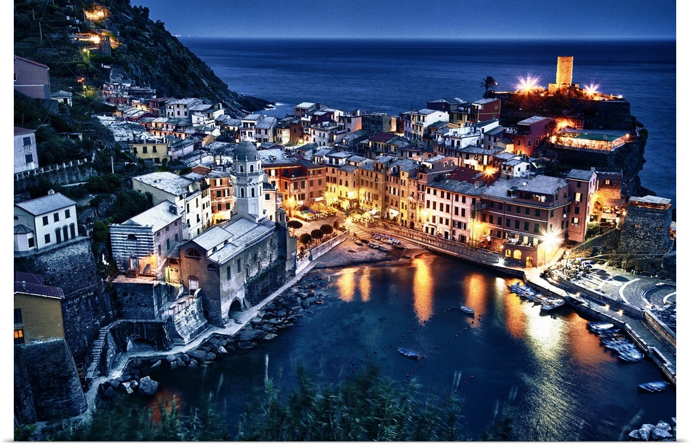 Aerial view of a seaside town in Cinque Terre, Italy at night with houselights lighting up the night. Boats, the sea, clif...