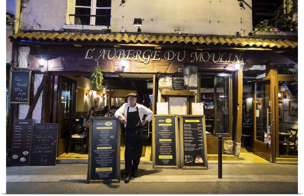 Waiter in front of a Paris cafe at night