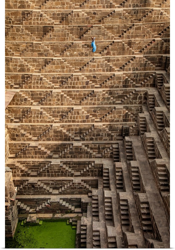 Woman with blue Sari walking to get water in the Chand Baori Step Well in India.