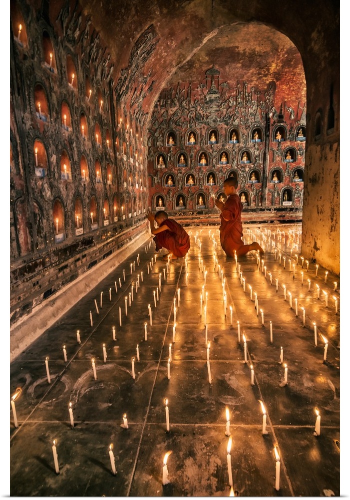 Young monk praying with candles in his monastery in Myanmar.
