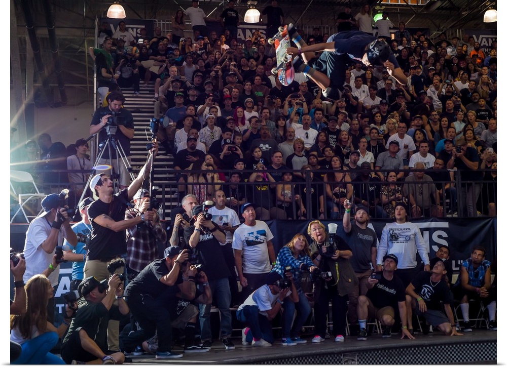 Austin Poynter jumping with his skateboard in front of a crowd at  Vans Off The Wall Skatepark in Huntington Beach, Califo...