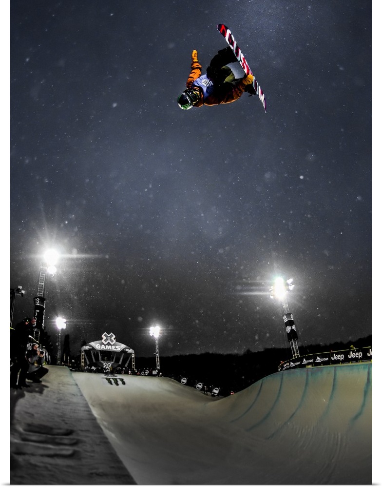 Snowboarder performing a trick in the air over a course at night, XGames, Aspen, Colorado, 2016.