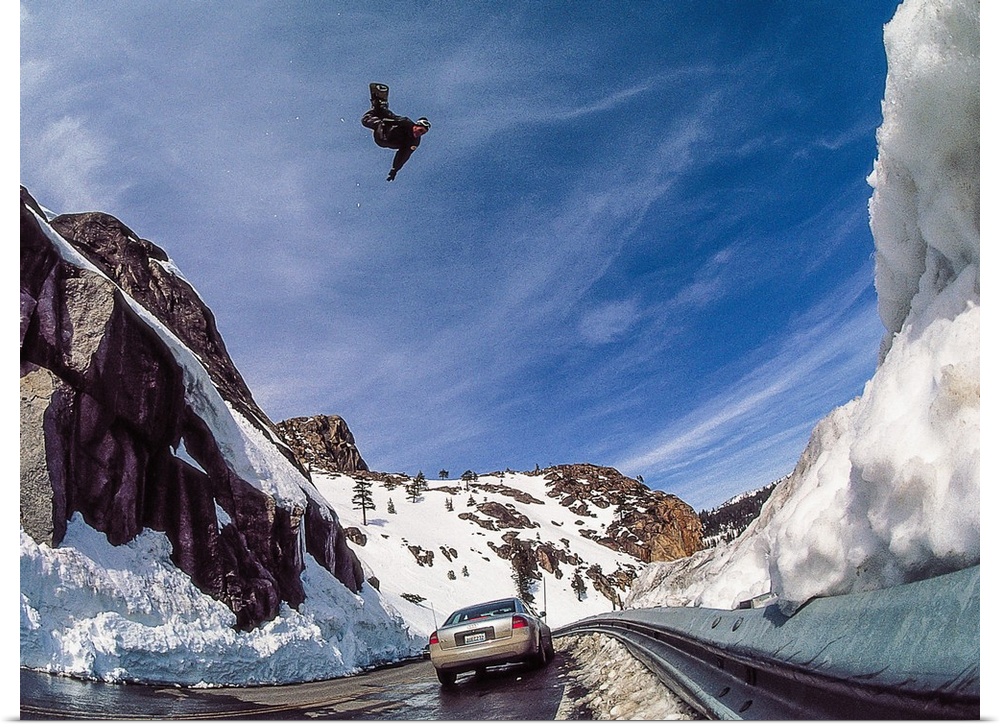 Nate Mott flying on his snowboard over the Donner Summit, as a car passes by below, California, mid 90s.