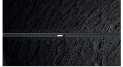 Road With White Car Surrounded By Black Volcanic Lava