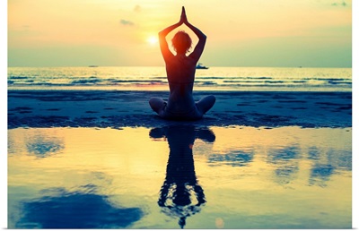 Woman sitting in lotus pose on the beach during sunset