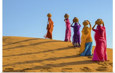 Women Carrying Jugs Of Water In The Hot Summer Desert