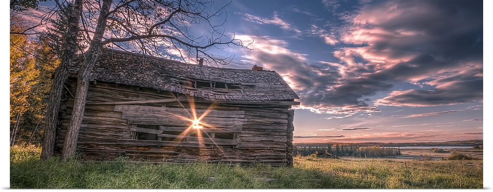 Sunrise beaming through the slats of an old Canadian prairie barn overlooking a field.