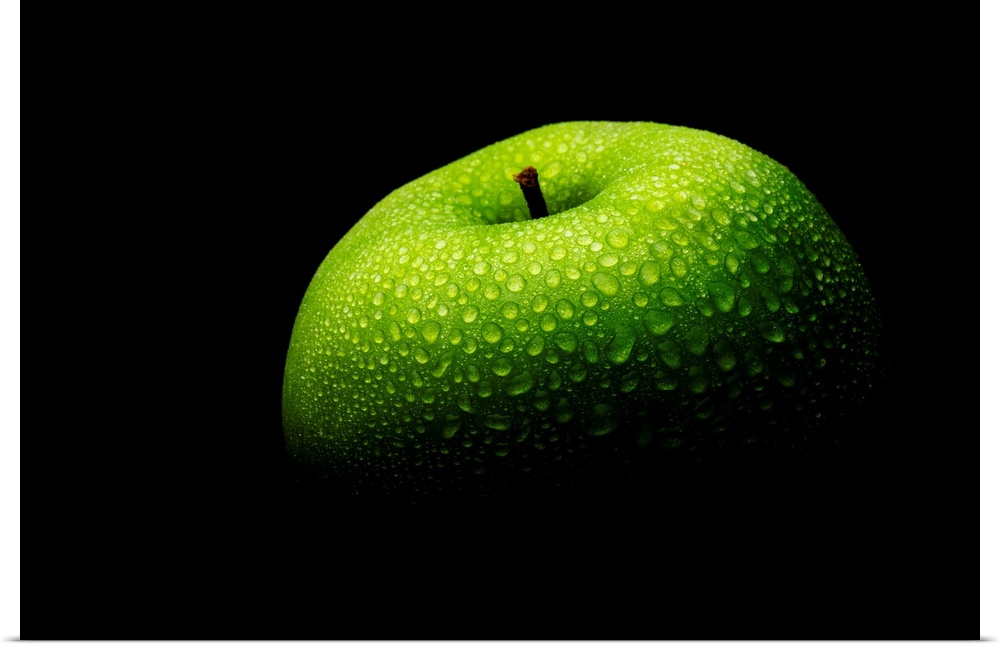 A close up photograph of a fresh Granny Smith apple with waterdrops.