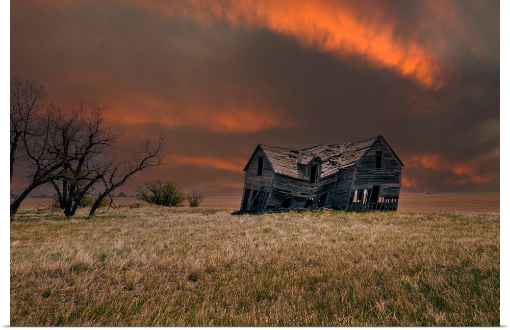 An old abandoned farm house with stormy skies at sunset in the Canadian prairies.