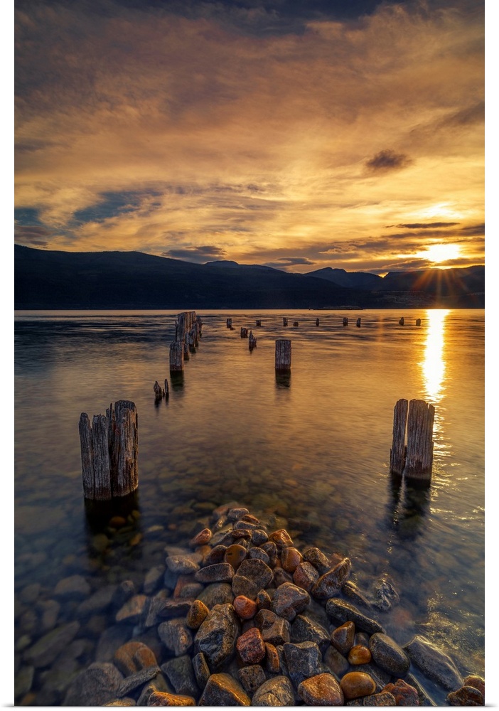 Sunset on Okanagan Lake British Columbia, Canada overlooking abandoned dock pilings and lake rocks.