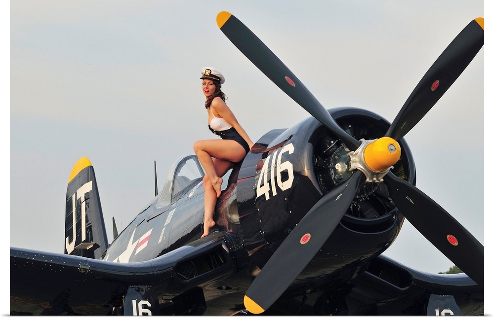 1940's style Navy pin-up girl sitting on a vintage World War II Corsair fighter plane.