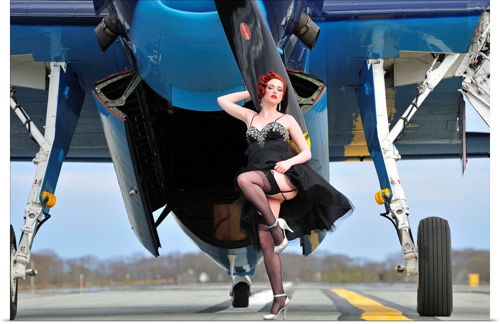Beautiful 1940's style pin-up girl in cocktail dress posing in front of a TBM Avenger.