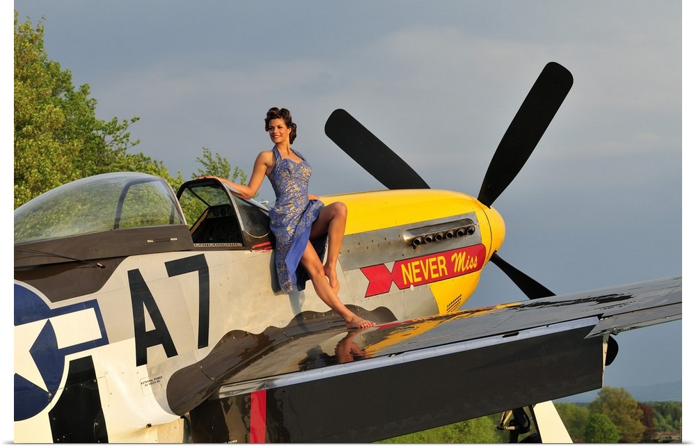 Beautiful 1940's style pin-up girl standing barefoot on the wing of a P-51 Mustang.