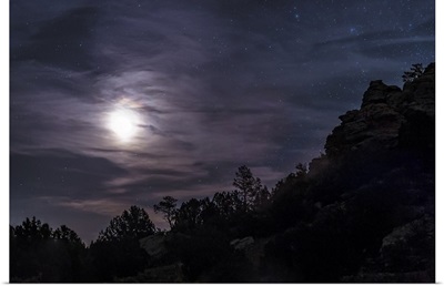 A bright moon rises through clouds over a hill in Oklahoma