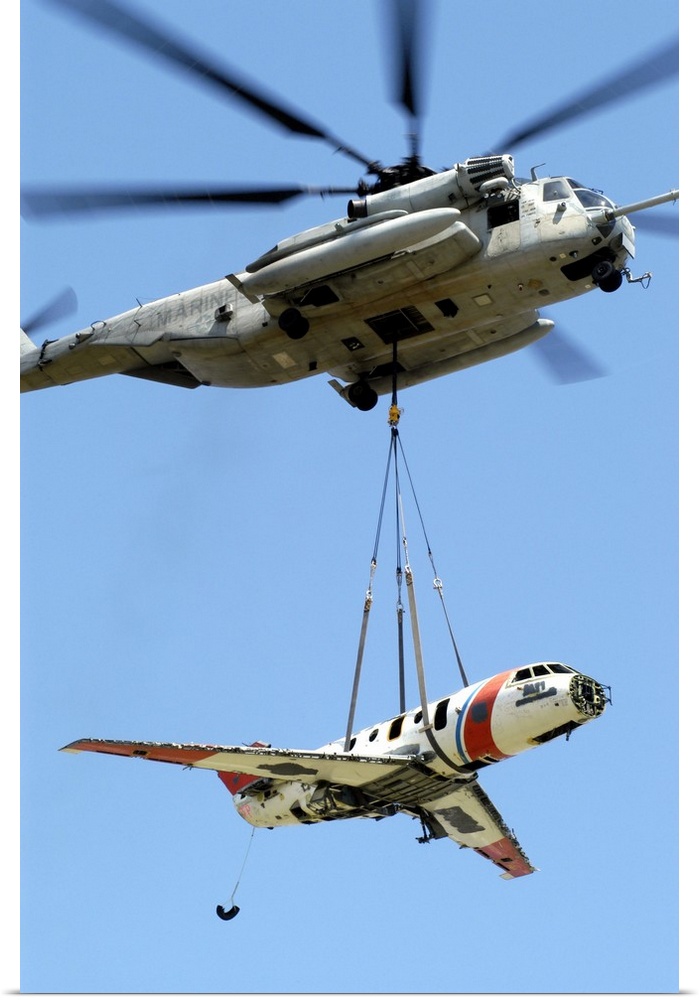 A CH-53 Sea Stallion lifts a HU-25 Guardian Coast Guard aircraft.