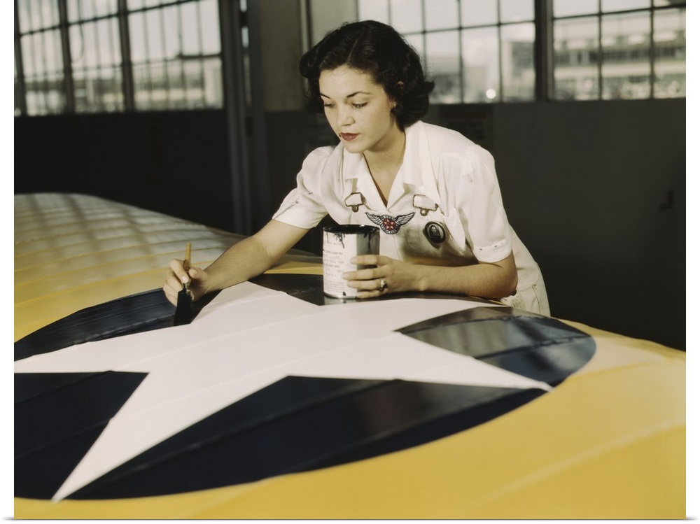 August 1942 - A civil service worker paints the American insignia on a repaired Navy plane wing at Naval Air Station Corpu...