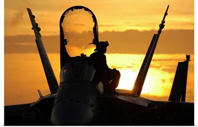 A plane captain enjoys a sunset from atop an F/A-18 Hornet
