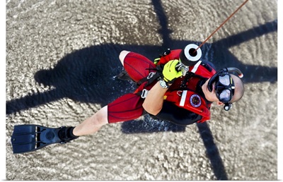 A rescue swimmer gets hoisted into an MH-60 Jayhawk helicopter