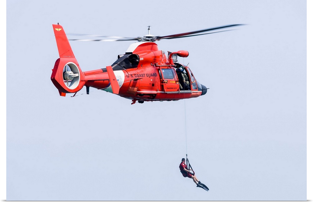 A rescue swimmer is lowered from a U.S. Coast Guard HH-65 Dolphin helicopter.