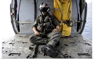 A Search And Rescue Swimmer Sits In The Back Of An MH-60S Sea Hawk