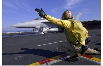 A shooter signals the launch of an F/A-18 Super Hornet