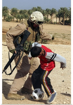 A soldier plays soccer with an Iraqi boy