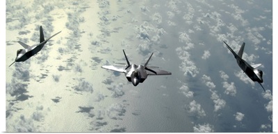 A three-ship formation of F-22 Raptors flies over the Pacific Ocean