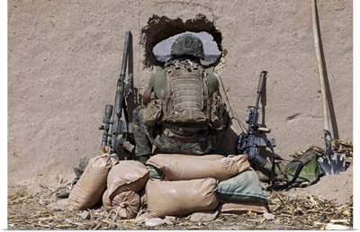 A U.S. Marine sniper observes his sector at a patrol base near Sangin, Afghanistan