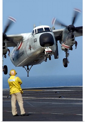 A US Navy officer observes a C2A Greyhound aircraft landing onboard USS Harry S Truman