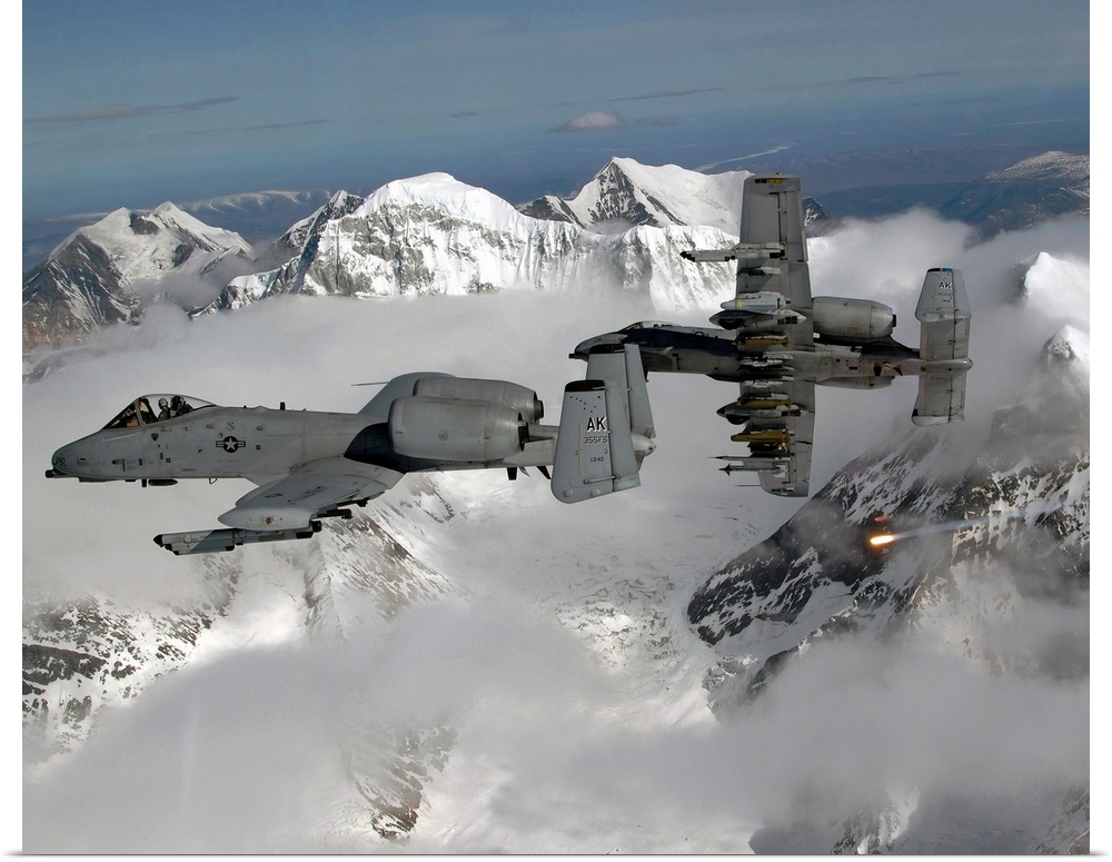 Big, horizontal photograph of two A10 Thunderbolt IIs flying through the clouds, above snow covered mountains.
