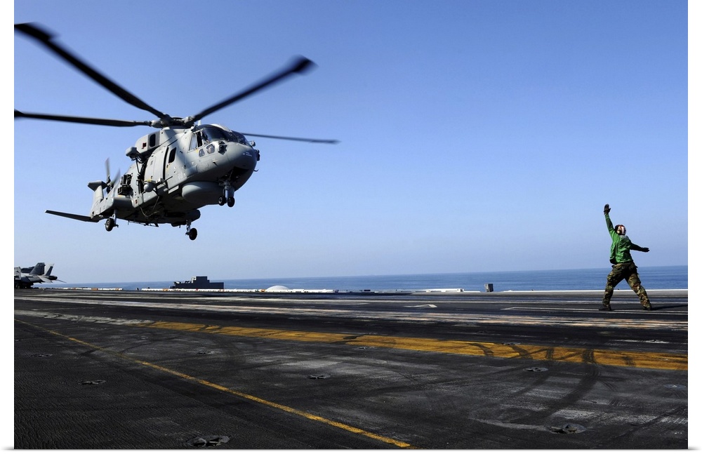Arabian Sea, October 24, 2011 - Airman directs an EH-101 Merlin helicopter onto the flight deck aboard the Nimitz-class ai...