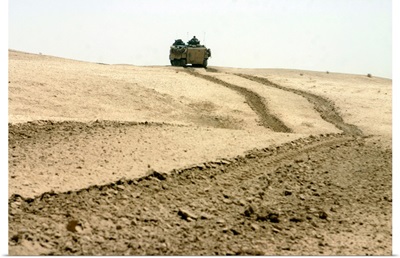 An amphibious assault vehicle rolls through a desert field