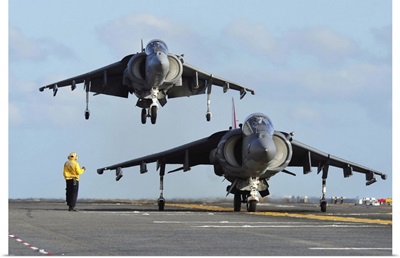 An AV-8B Harrier prepares for takeoff as another lands aboard USS Makin Island