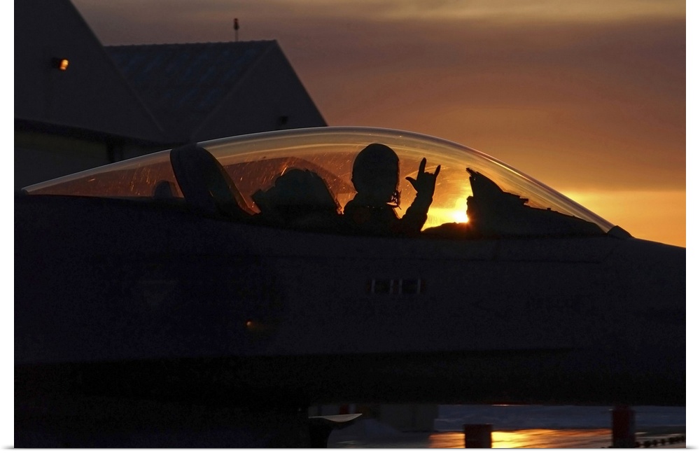 An F16 Fighting Falcon Fighter Pilot gives the mission accomplished sign while taxiing