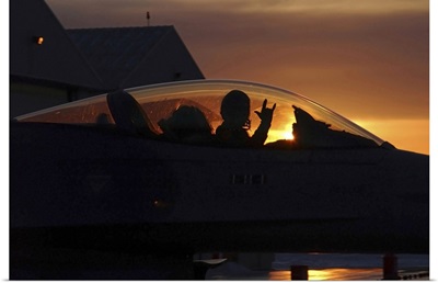 An F16 Fighting Falcon Fighter Pilot gives the mission accomplished sign while taxiing