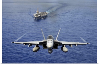 An F/A-18E Super Hornet flying above USS John C. Stennis
