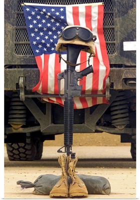 An M16A2 service rifle a pair of boots and a helmet stand in tribute to a fallen soldier