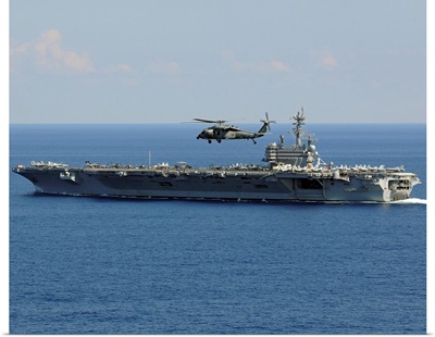 An MH 60S Seahawk helicopter flies over USS George H.W. Bush