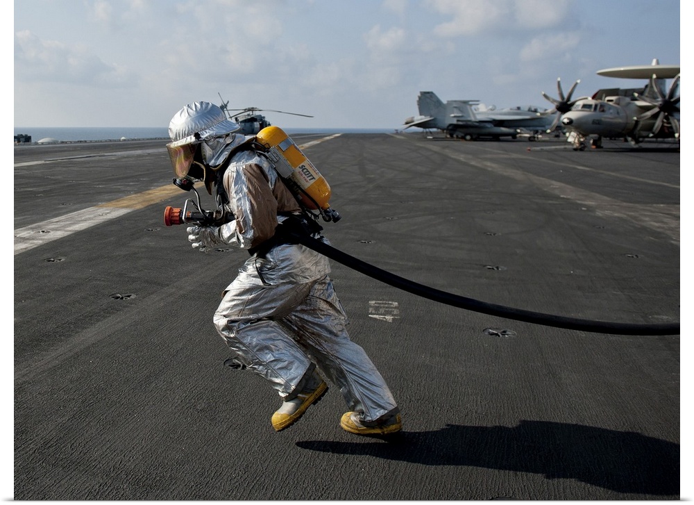 Arabian Sea, January 13, 2012 - Aviation Boatswain's Mate carries a fire hose during a flight deck fire drill aboard the N...
